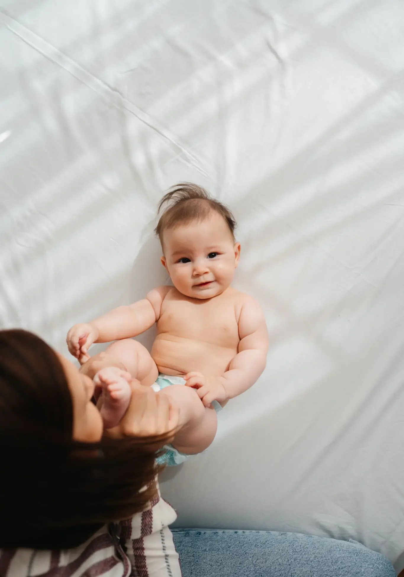 Smiling baby lying on white bed
